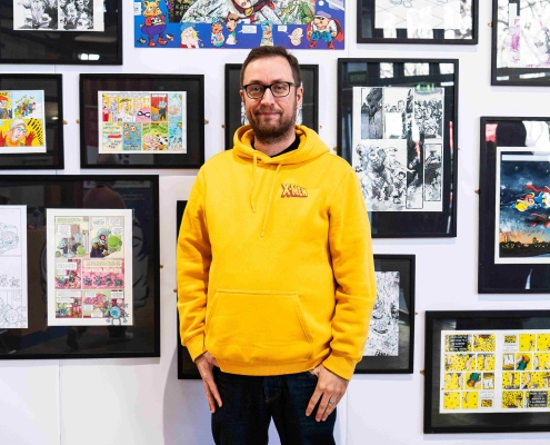 Andy Genen posant devant ses créations lors de l'exposition sur la BD luxembourgeoise